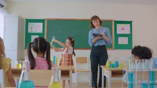 Adorable student learn with teacher in classroom at elementary school.