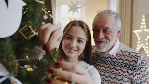 Woman and Senior Man Decorate Christmas Tree Together