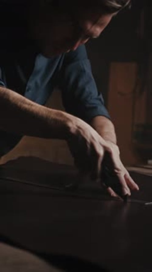 Nähwerkstatt Nahaufnahme männlicher Hände beim Auftrennen von Nähten mit einem Leinwandmesser im Tailor Studio