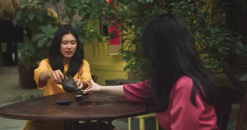Zwei schöne asiatische Frauen, die sich beim Teetrinken unterhalten Junge Touristen auf Vietnamesisch Traditionell