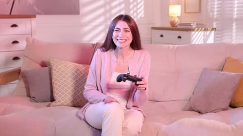 Smiling woman with controller playing video game on sofa at home