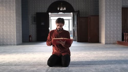Der Mann, der in der Moschee sitzt und den Koran liest, ein muslimischer Mann hält ein religiöses Buch,