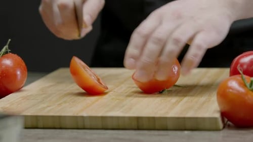 Hands of a Male Chef are Slicing a Juicy Red Ripe Tomato