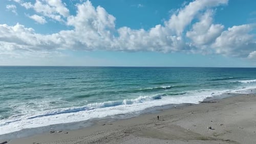 Aerial Video Stormy Waves Hit the Beach Leaving Dazzling Foam Trails Along the Sandy Coastline