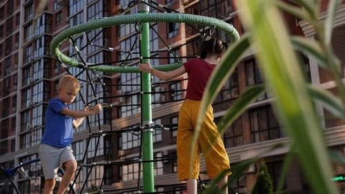 Children Climb the Grid on the Playground on a Hot Summer Day