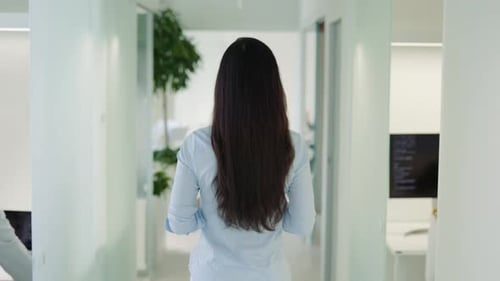 Unknown Businesswoman with Long Black Hair Walking Through Office