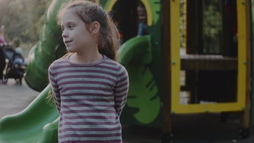 Little Girl Stands on the Playground Looking Around Family Child and Healthy Lifestyle Concept