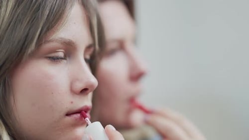 Mutter und Tochter tragen gemeinsam Lipgloss auf