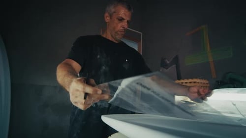 Surf board factory. Adult male shaper creates the surfing board on the factory