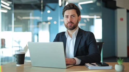 Confident Professional Working on Laptop in Modern Office