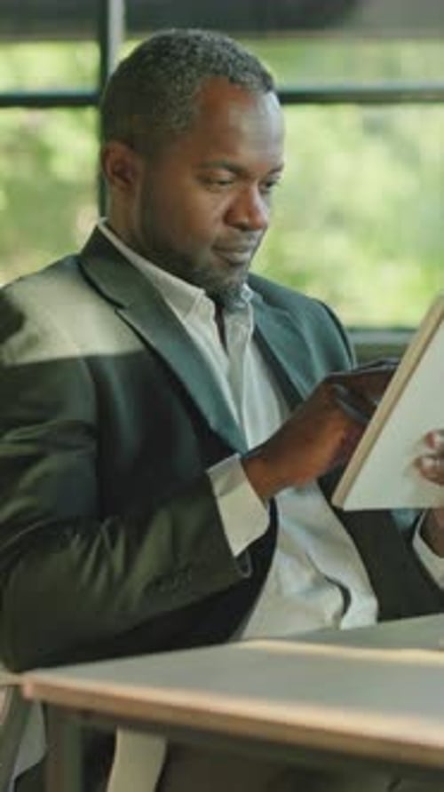 A Professional Man Reads in a Modern Office Showcasing Calm Creativity Ambition and Intellect
