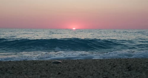 Fundo romântico do pôr do sol no mar. Horizonte de cor roxa, céu sem nuvens e ondas em direção a uma pedra