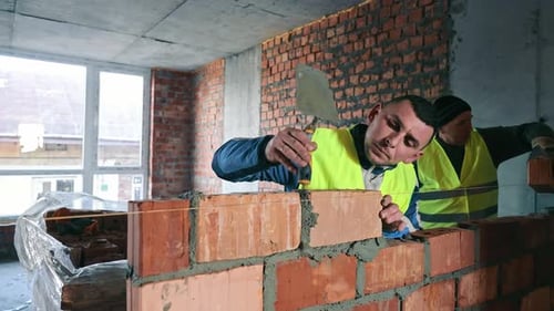 Construction Worker Building a Brick Wall A Focused Construction Worker in a Reflective Vest