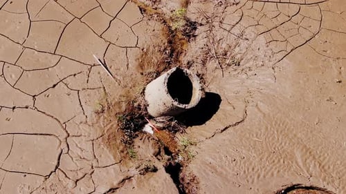 Drone Rotates Around Eroded Well in Cracked Mud Landscape – Drought Concept