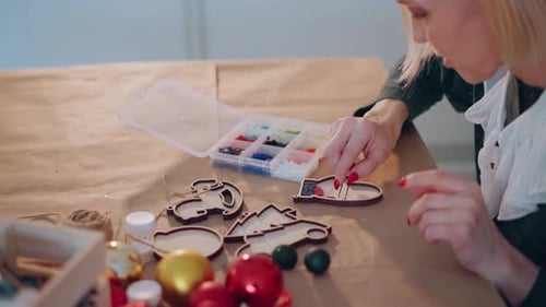 Woman Decorating Wooden Christmas Ornaments with Colorful Rhinestones