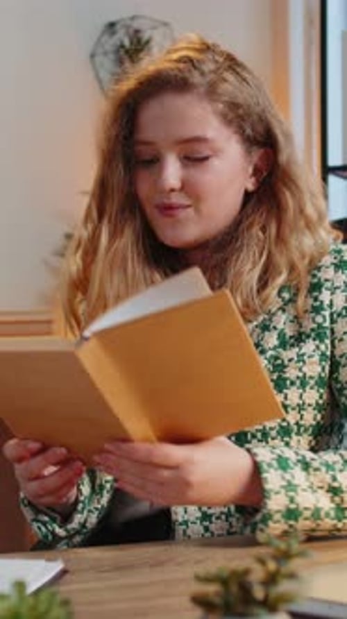 Woman Reading Book Indoors at Wooden Desk