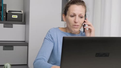 Close up businesswoman work from home office at desk look at laptop screen hold smartphone