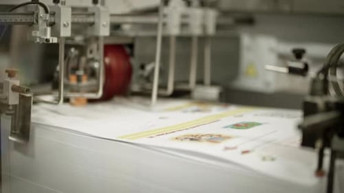 Close up of a printing machine, printed paper traveling from the pile of paper away on the side.