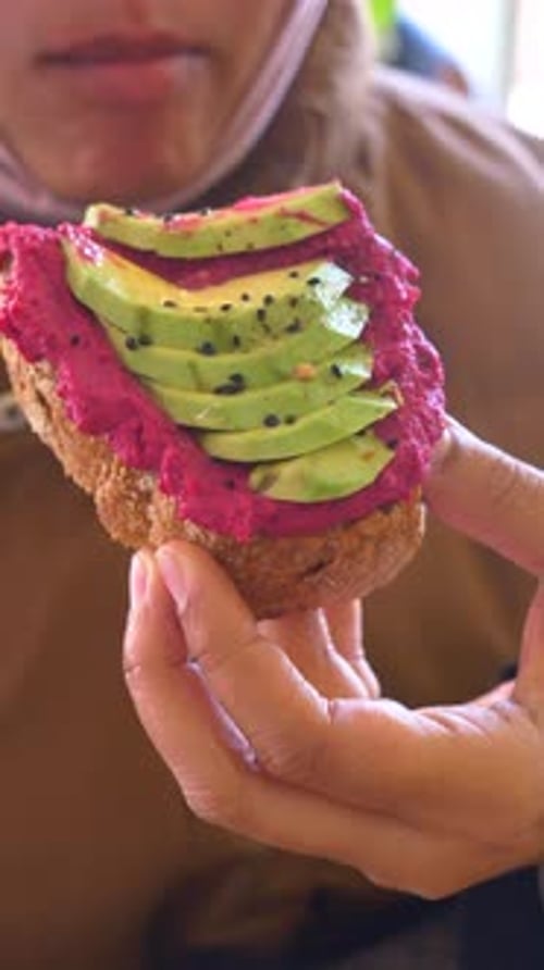 Woman Holds Avocado and Beet Hummus Toast