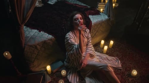 Pale Vampire Woman Enjoying Glass of Blood Surrounded by Candlelight