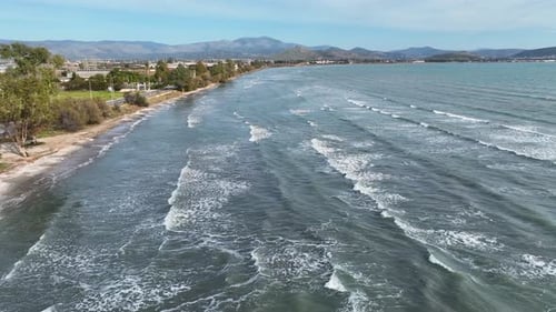 Aerial footage of long waves on the beach on a sunny day