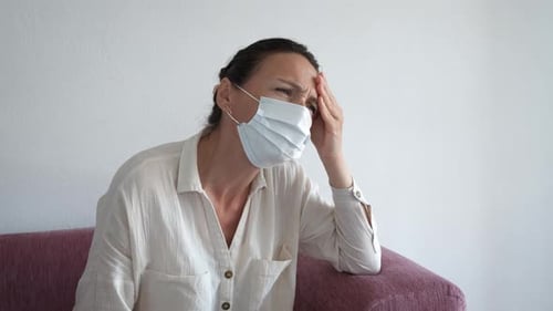 Woman Wearing a Mask with a Headache Indoors