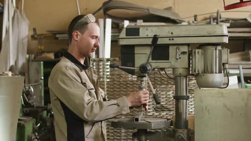 Junger Mechaniker arbeitet mit Werkzeugmaschine in der Fabrik