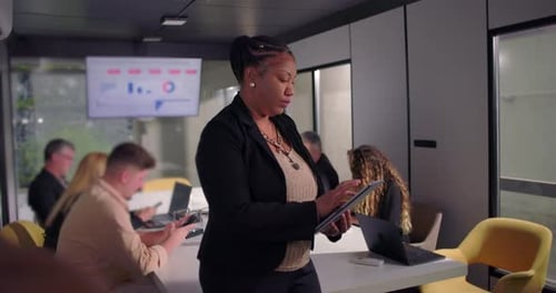 African American businesswoman standing in office using digital tablet, focused on work