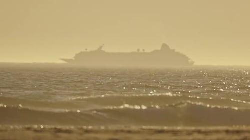 A Large Ship is Sailing in the Ocean with the Sun Setting in the Background