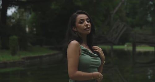 portrait of a beautiful woman posing in a park in a green dress