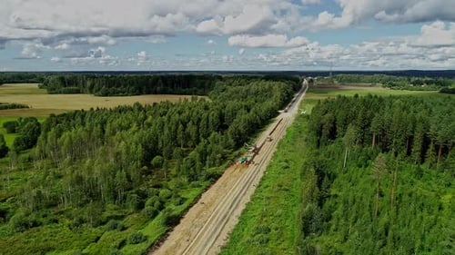 Aerial flyback view of road construction machinery working across Latvia forest