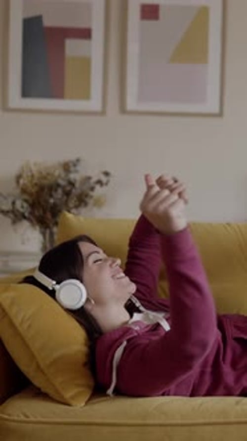 Woman Lying on Couch Listening to Music