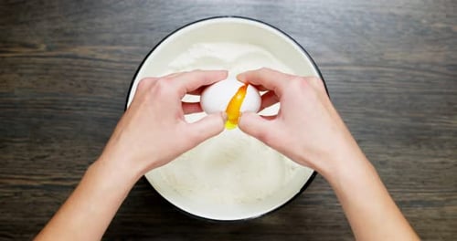 Cracking Egg into Flour for Baking Overhead Shot