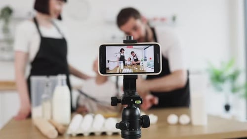 Blogueros familiares graban un tutorial de cocina en casa juntos en una cocina moderna