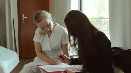 Woman Signing Document During Home Healthcare Visit