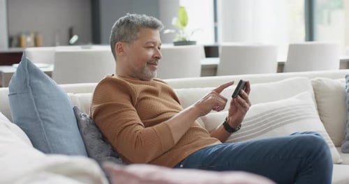 Adult Using Smartphone on Sofa in Home
