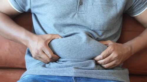 Adult Male Holding Stomach Sitting on Couch