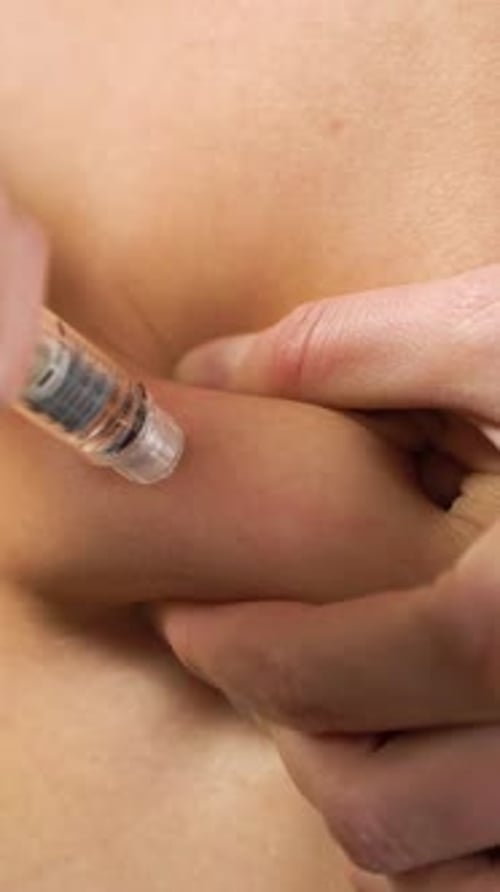Eine Frau injiziert zu Hause Hormone mit einer Spritze in den Magen