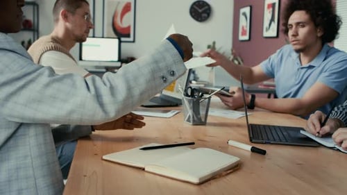 Multi-Ethnic Colleagues Sitting at Table, Working with Paper Documents in Office