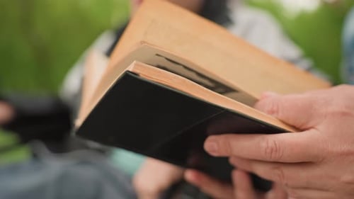 Individual Flipping Pages In Peaceful Park Setting Person Leisurely Turning Pages Of Compact Book