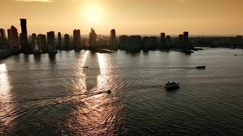 Golden hour in majestic New York. Boats go by the Hudson River. Silhouettes of skyscrapers