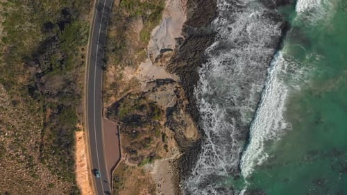 Aerial drone view of car driving on open road on coast line