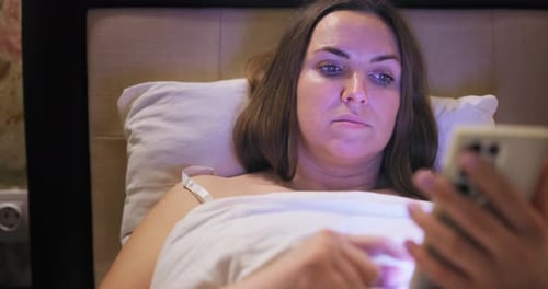 Woman Lies in Bed Using her Phone