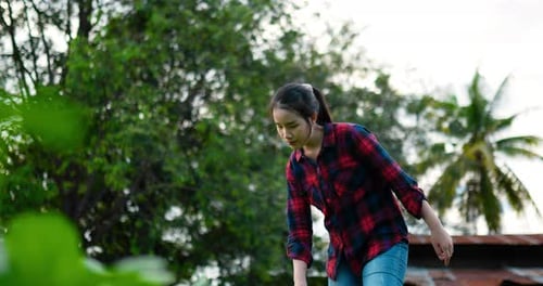 Young female farmer use watering can pour water on green leaf