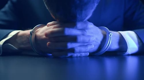 Close Up of Man in Handcuffs at Desk