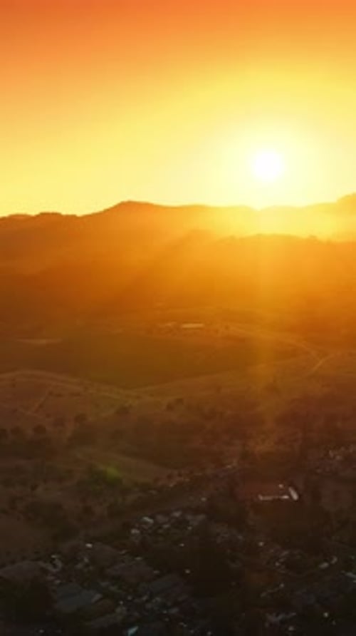 Bright sun setting behind the mountains. Beautiful valley of Napa with lots of cozy houses.