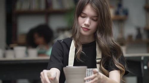 Young women is making earthenware at workshop.