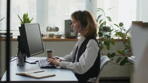 Cheerful Girl Working on Computer and Talking with Customer in Call Centre