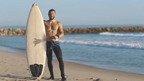 Male Surfer Posing with Board on Sandy Beach