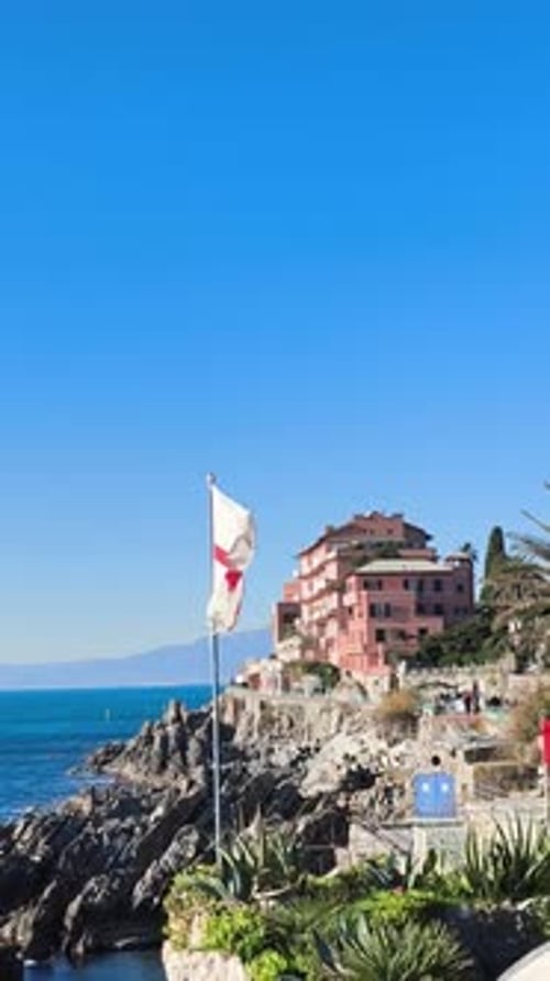 Coastal Building and Flag Along Rocky Shoreline on Sunny Day